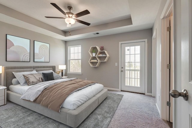 bedroom featuring ceiling fan, light colored carpet, a tray ceiling, and access to exterior