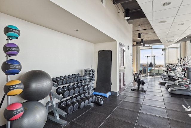 exercise room featuring a paneled ceiling and expansive windows