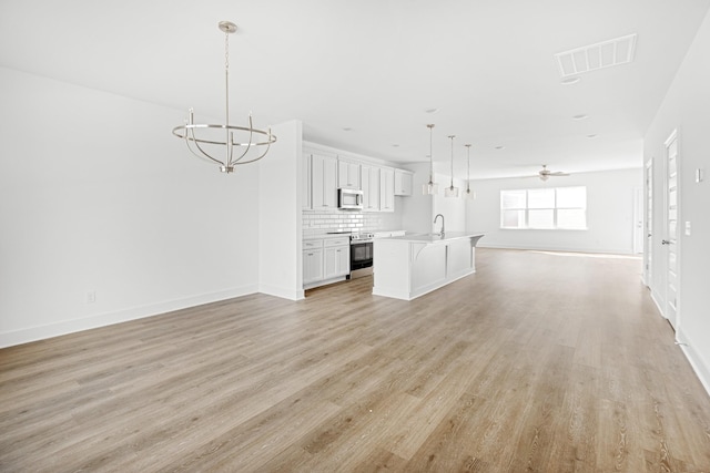 5061 Greentree Dr, Smyrna, TN 37167 - unfurnished living room with a chandelier, light wood finished floors, ceiling fan, and baseboards