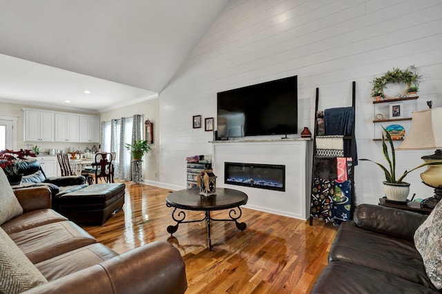 living room with hardwood / wood-style floors, crown molding, and high vaulted ceiling