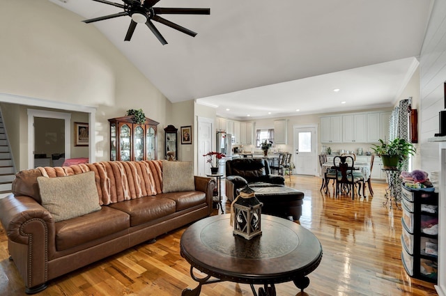 living room with high vaulted ceiling, ceiling fan, and light wood-type flooring