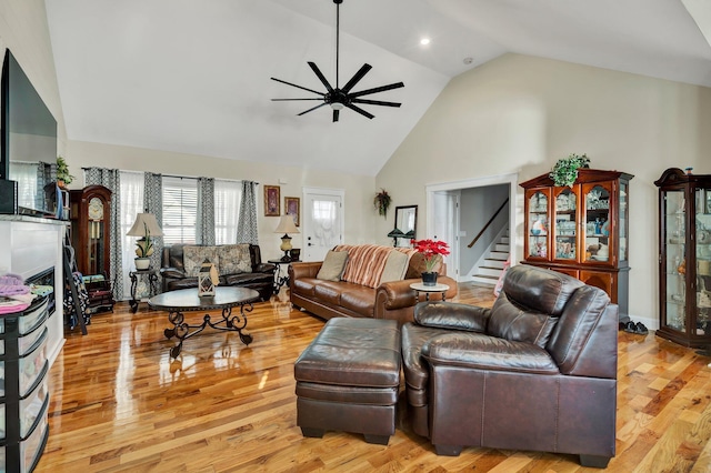 living room with high vaulted ceiling, ceiling fan, and light hardwood / wood-style flooring