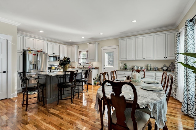 dining room with crown molding, sink, and light hardwood / wood-style floors