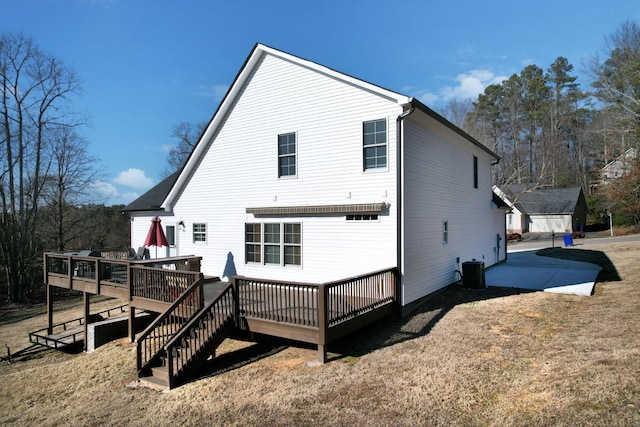 rear view of property featuring cooling unit, a deck, and a lawn