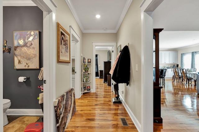 hallway with ornamental molding and light hardwood / wood-style floors