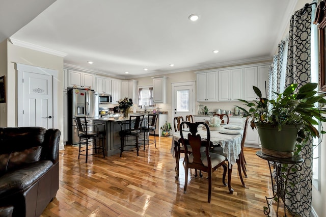 dining space featuring sink, crown molding, and light hardwood / wood-style flooring