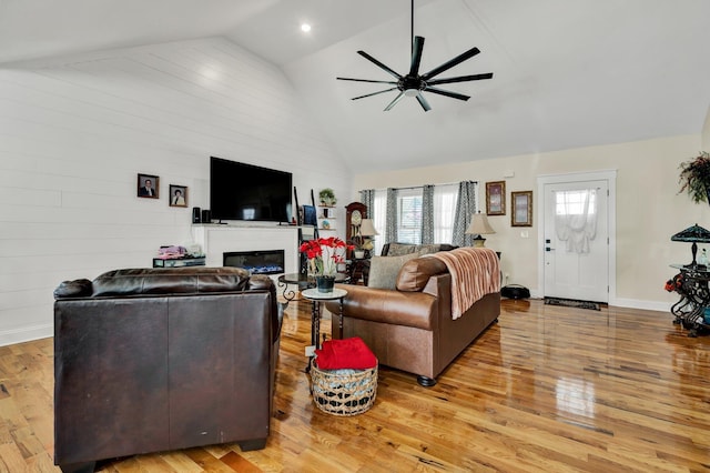 living room featuring light hardwood / wood-style flooring, high vaulted ceiling, and ceiling fan