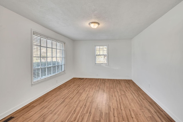 empty room featuring a textured ceiling and light hardwood / wood-style floors