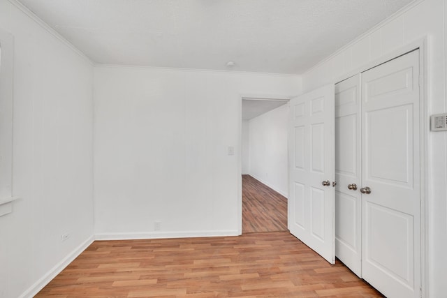 unfurnished bedroom with ornamental molding, a closet, and light wood-type flooring