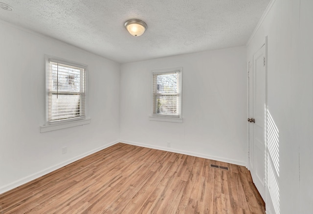 spare room with ornamental molding, light hardwood / wood-style floors, and a textured ceiling