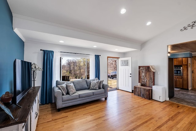 living room featuring ornamental molding, lofted ceiling, and light wood-type flooring