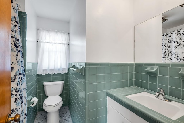 bathroom featuring tile patterned flooring, vanity, tile walls, and toilet