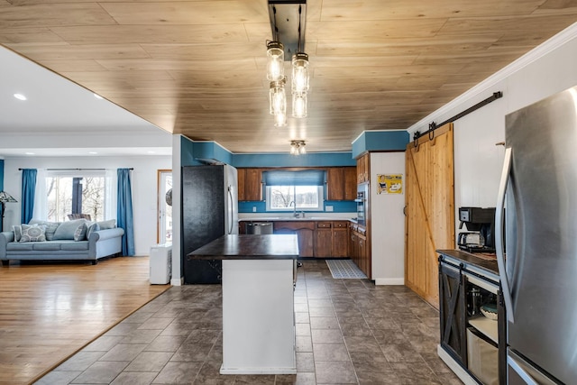 kitchen with sink, crown molding, a barn door, and appliances with stainless steel finishes