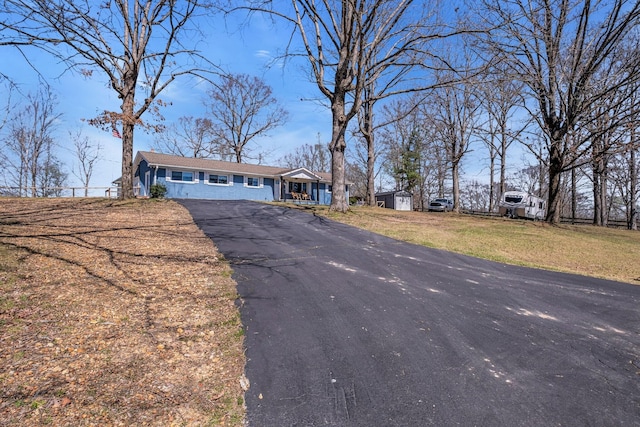 ranch-style home with a front lawn and a storage unit