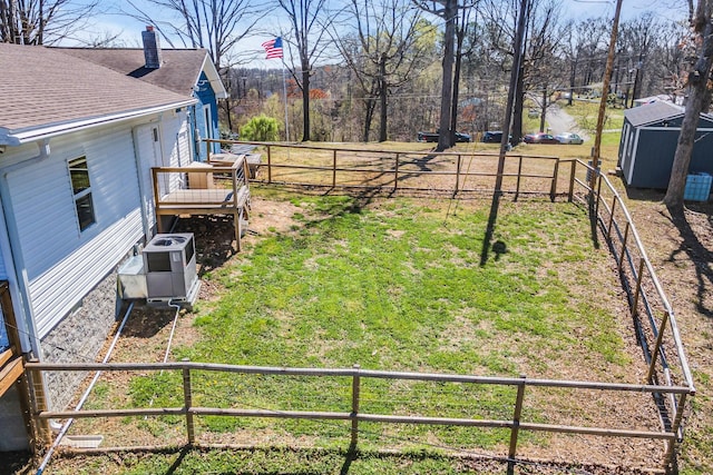 view of yard featuring a wooden deck, ac unit, and a storage shed