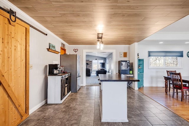 kitchen featuring a breakfast bar area, wooden ceiling, stainless steel refrigerator, ornamental molding, and a barn door