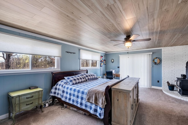 carpeted bedroom featuring ornamental molding, a wood stove, ceiling fan, and wood ceiling