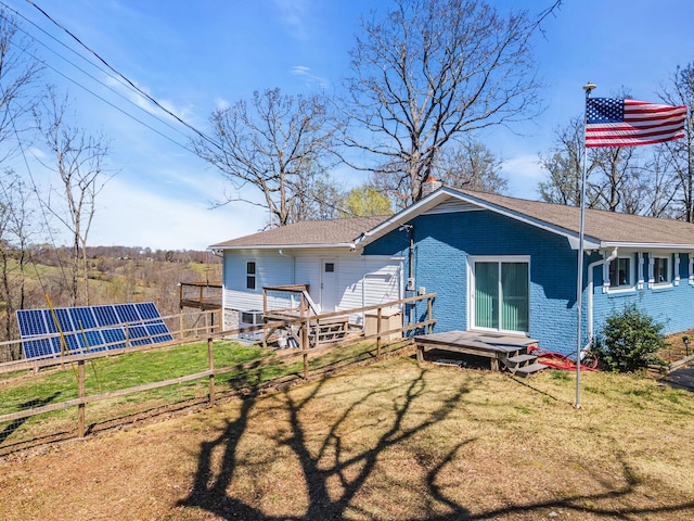 back of house featuring a yard, central air condition unit, and solar panels