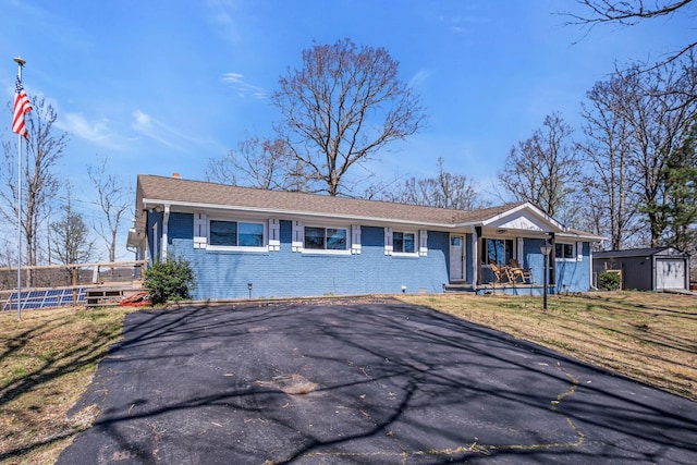 ranch-style house with a shed, a front lawn, and a porch