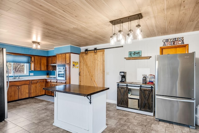 kitchen with sink, stainless steel appliances, a kitchen breakfast bar, decorative light fixtures, and a barn door