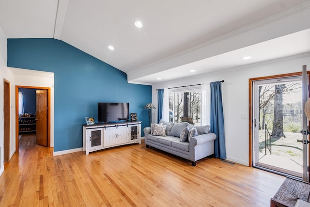 living room with vaulted ceiling, ornamental molding, and light wood-type flooring