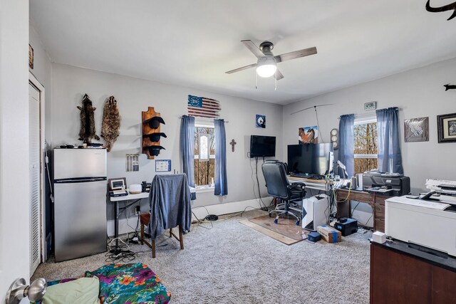 home office with light carpet, ceiling fan, and a healthy amount of sunlight