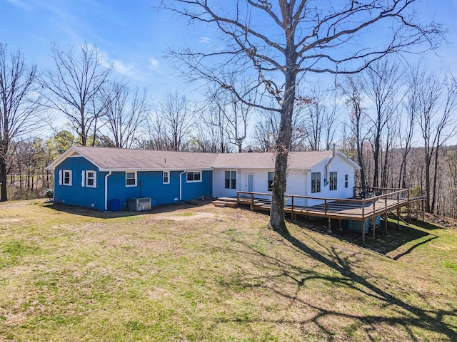 rear view of property with a wooden deck, central AC unit, and a lawn