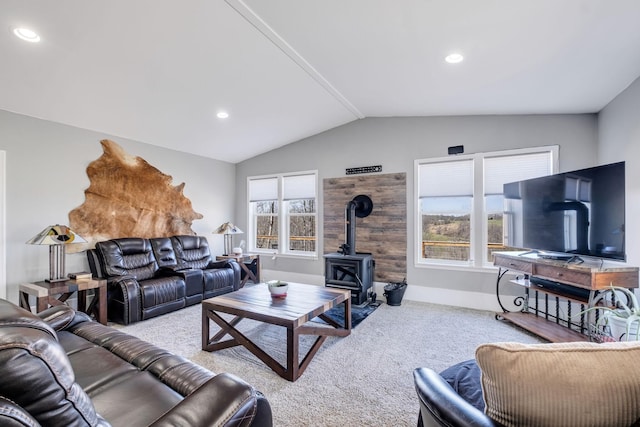 living room featuring lofted ceiling, plenty of natural light, light carpet, and a wood stove