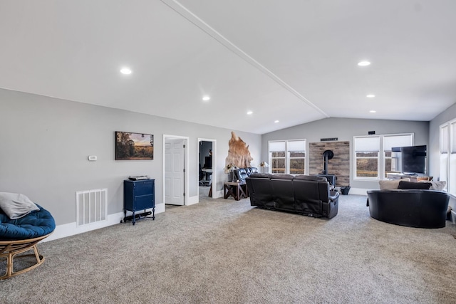 living room with carpet flooring, vaulted ceiling, and a wood stove