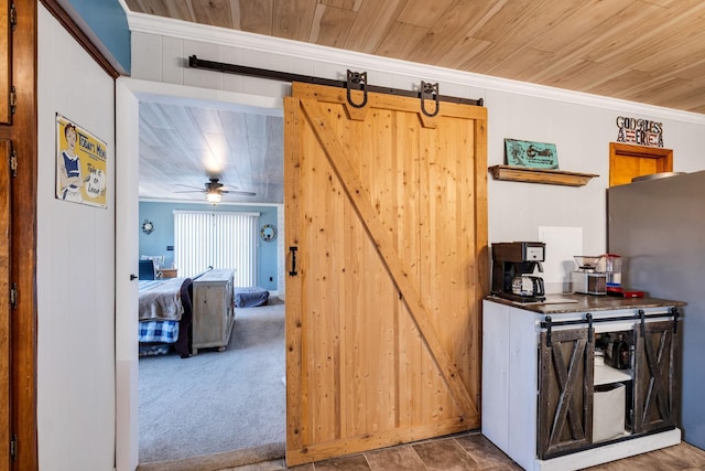 interior space with wood ceiling, carpet flooring, a barn door, and crown molding