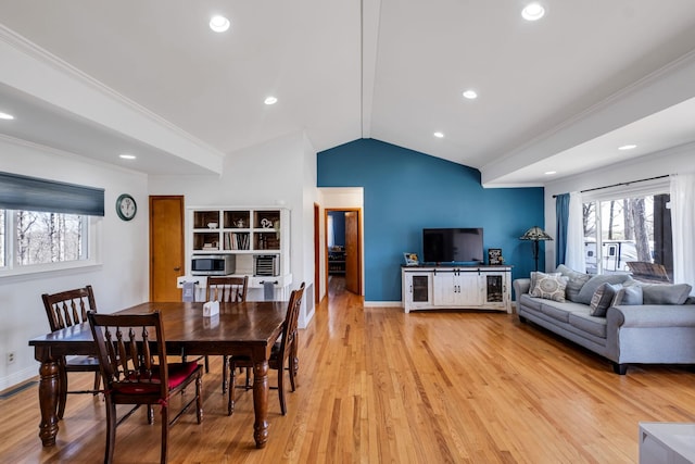 living room with crown molding, lofted ceiling, and light wood-type flooring