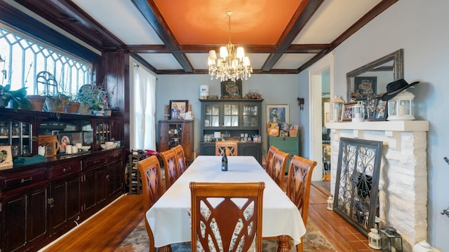 dining area featuring beamed ceiling, coffered ceiling, an inviting chandelier, and light hardwood / wood-style flooring