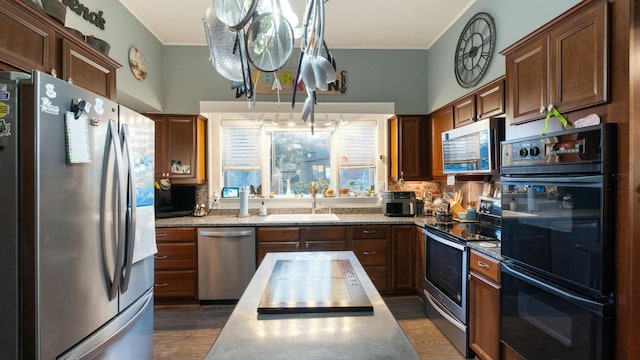 kitchen with dark hardwood / wood-style floors, ornamental molding, appliances with stainless steel finishes, and decorative light fixtures