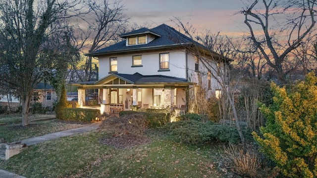 view of front of property with covered porch and a lawn