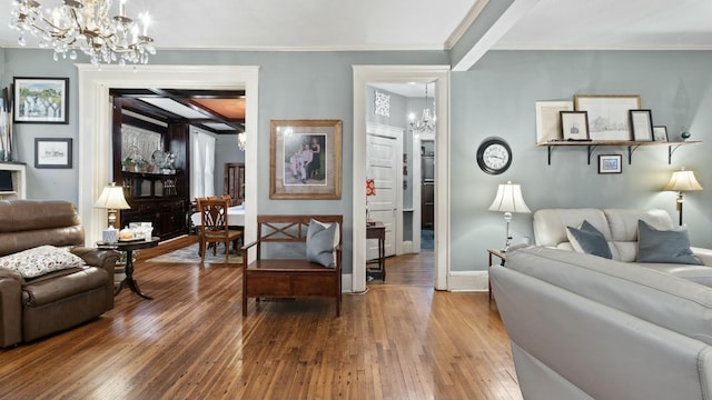 living room with beamed ceiling, wood-type flooring, crown molding, and an inviting chandelier