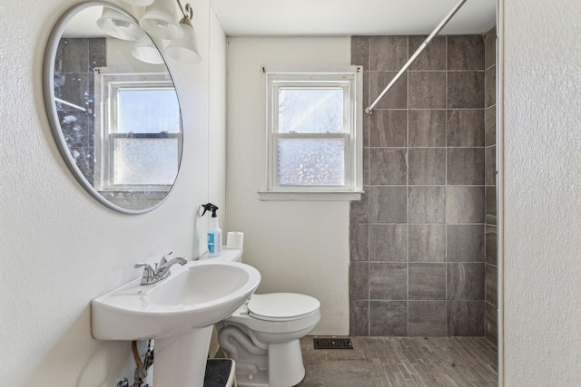 bathroom featuring toilet and tiled shower