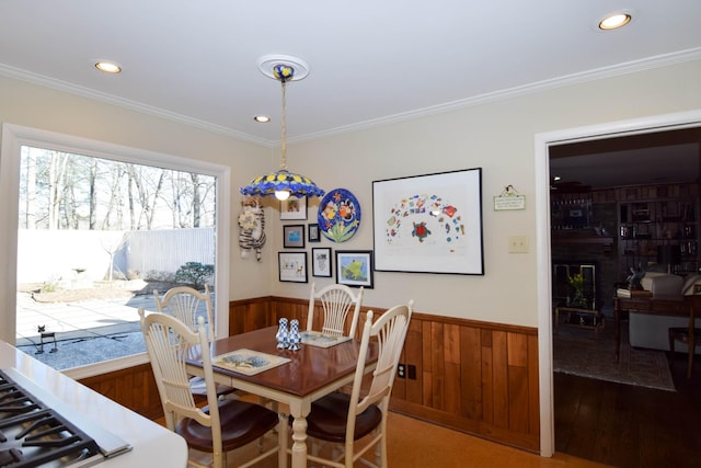 dining room with hardwood / wood-style flooring, ornamental molding, and wood walls