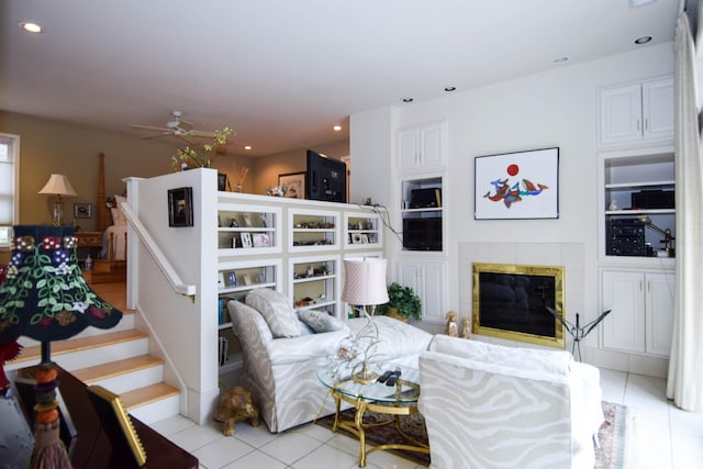 living room featuring light tile patterned flooring, ceiling fan, and a fireplace