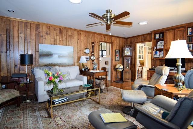 living room featuring crown molding, dark hardwood / wood-style floors, wooden walls, and ceiling fan