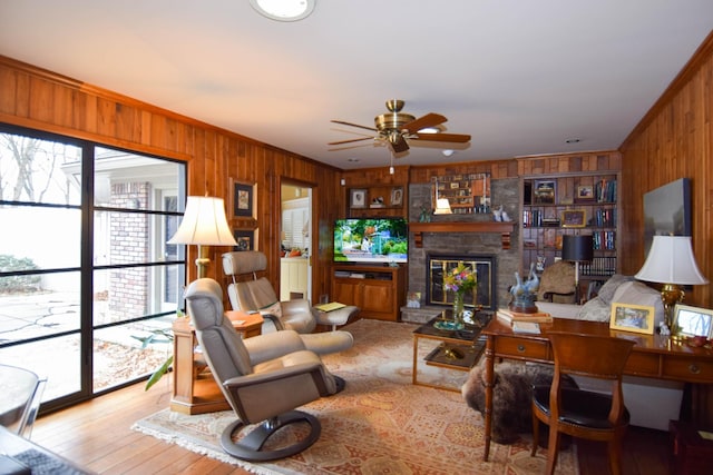 living room with ornamental molding, light hardwood / wood-style floors, a fireplace, and wood walls