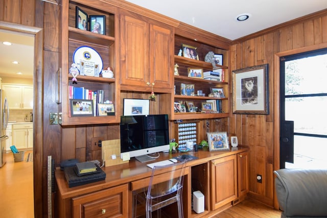 home office featuring crown molding, built in desk, light hardwood / wood-style floors, and wood walls