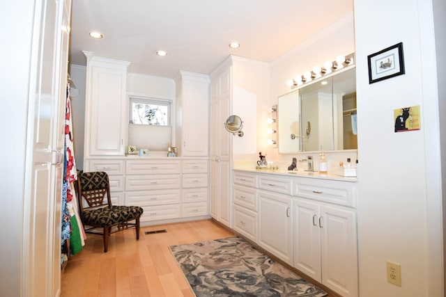 bathroom featuring ornamental molding, hardwood / wood-style floors, and vanity