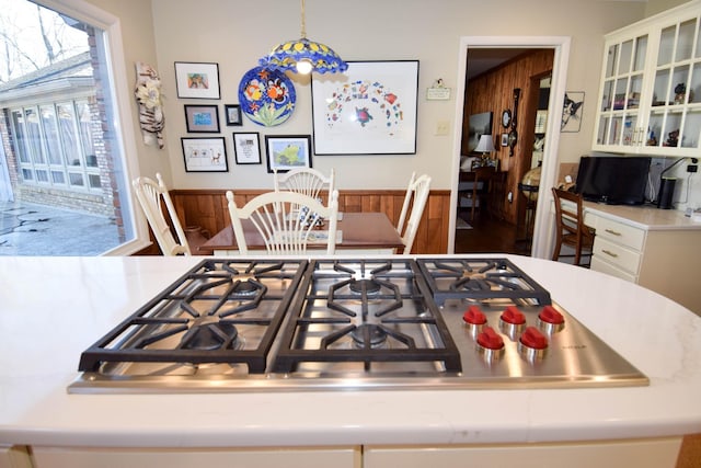 interior space featuring white cabinets, hanging light fixtures, and stainless steel gas stovetop