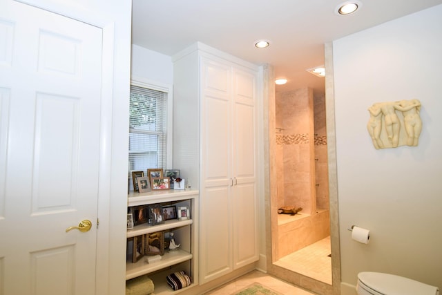 bathroom with tiled shower and toilet