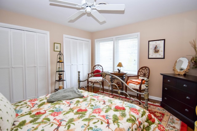 bedroom with ceiling fan, wood-type flooring, and two closets