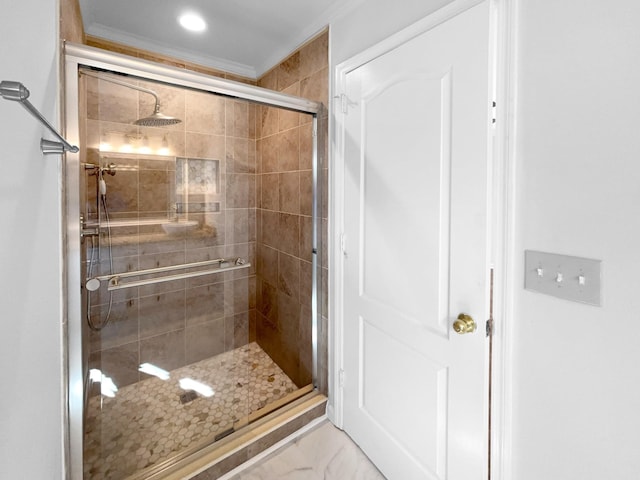 bathroom with crown molding and a shower with shower door