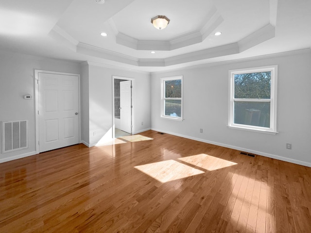 unfurnished bedroom featuring ornamental molding, light hardwood / wood-style flooring, and a tray ceiling