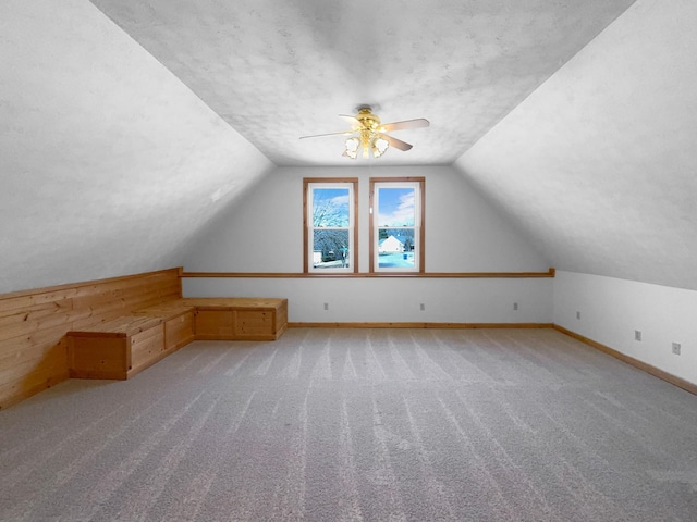 bonus room with ceiling fan, lofted ceiling, light carpet, and a textured ceiling