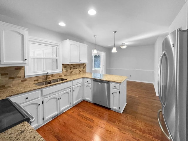 kitchen featuring sink, appliances with stainless steel finishes, white cabinets, decorative light fixtures, and kitchen peninsula