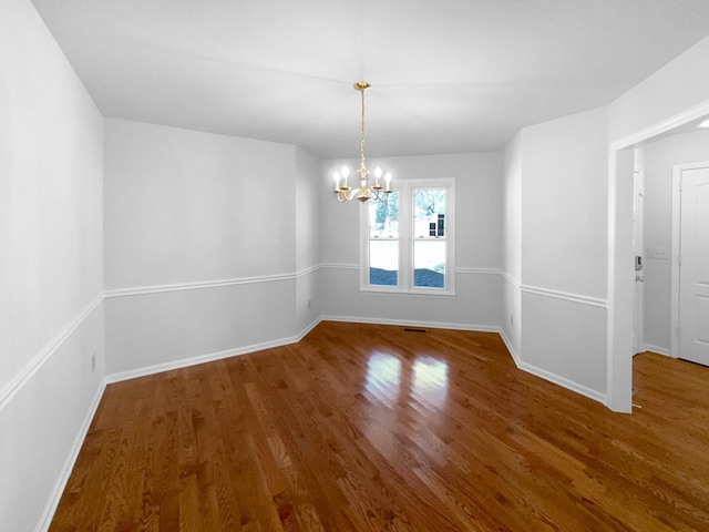 unfurnished room featuring hardwood / wood-style flooring and an inviting chandelier